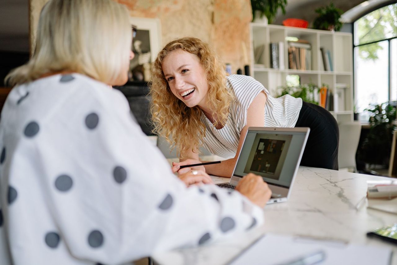 Twee ondernemers vergelijken samen kredietaanbieders op een laptop