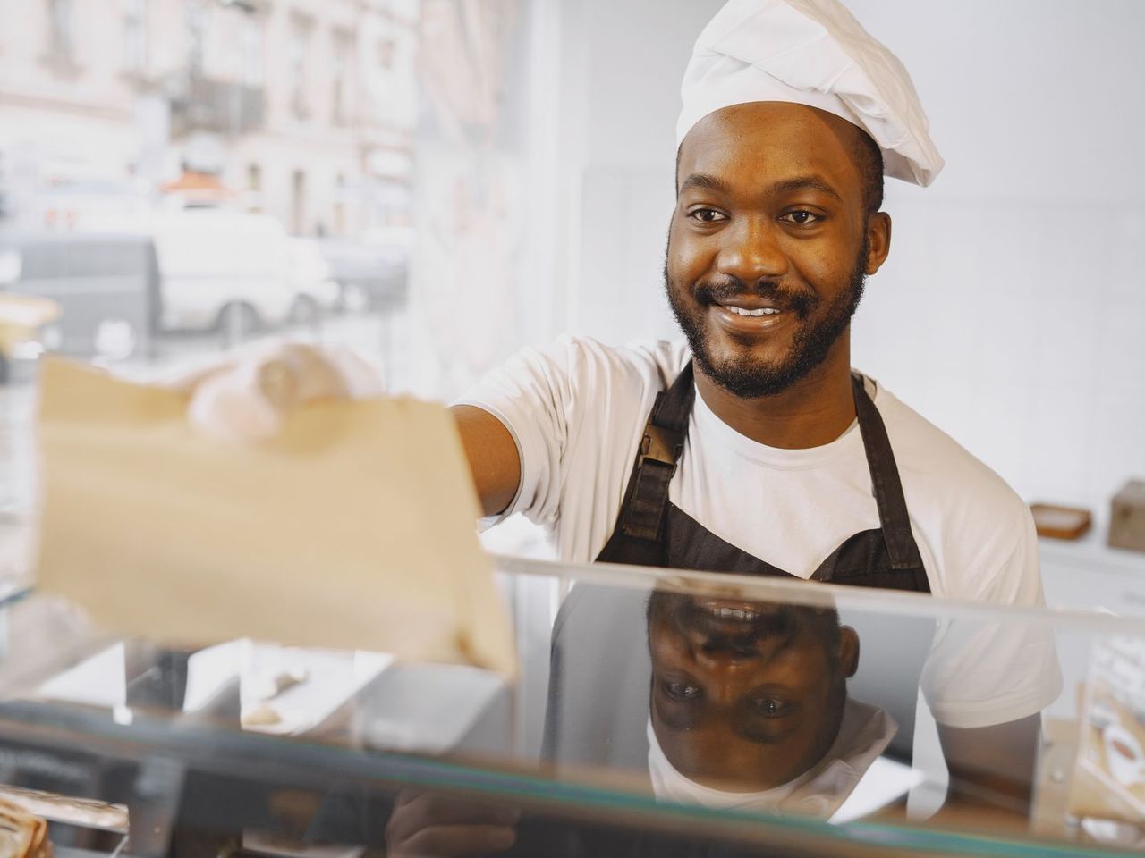 Lachende bakker overhandigt een bestelling over de toonbank